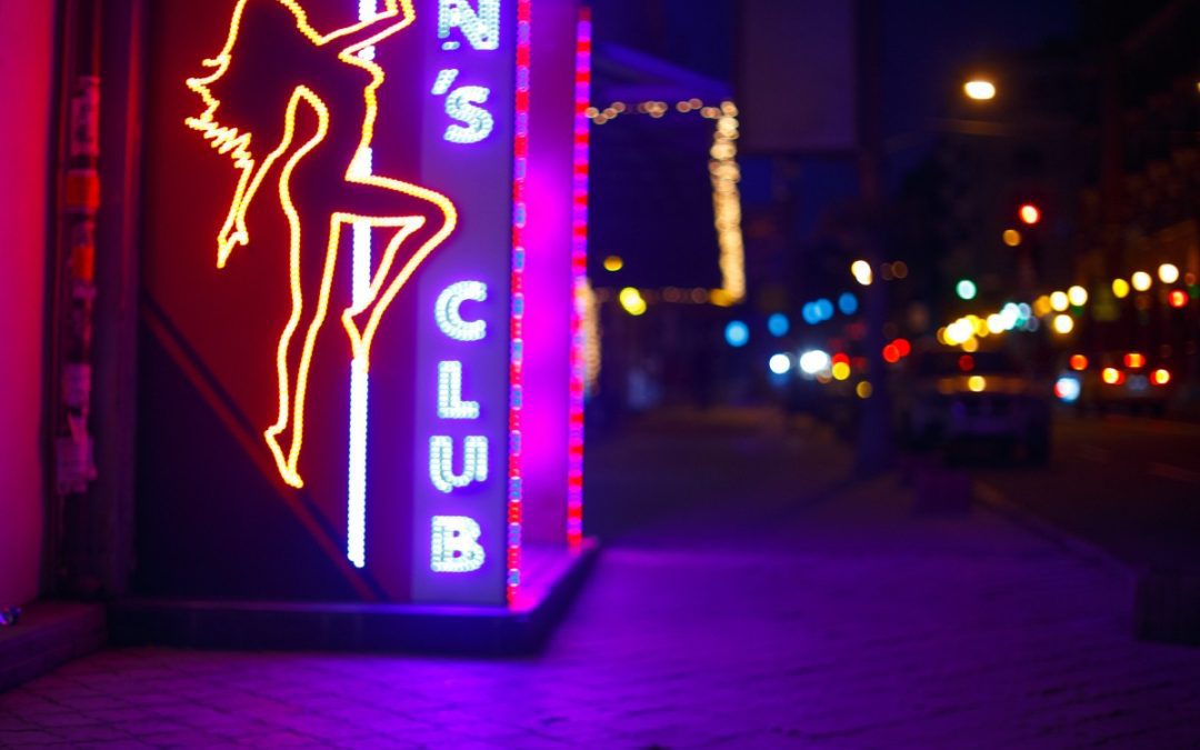 a neon sign that shoes a n outline of a woman on a pole.