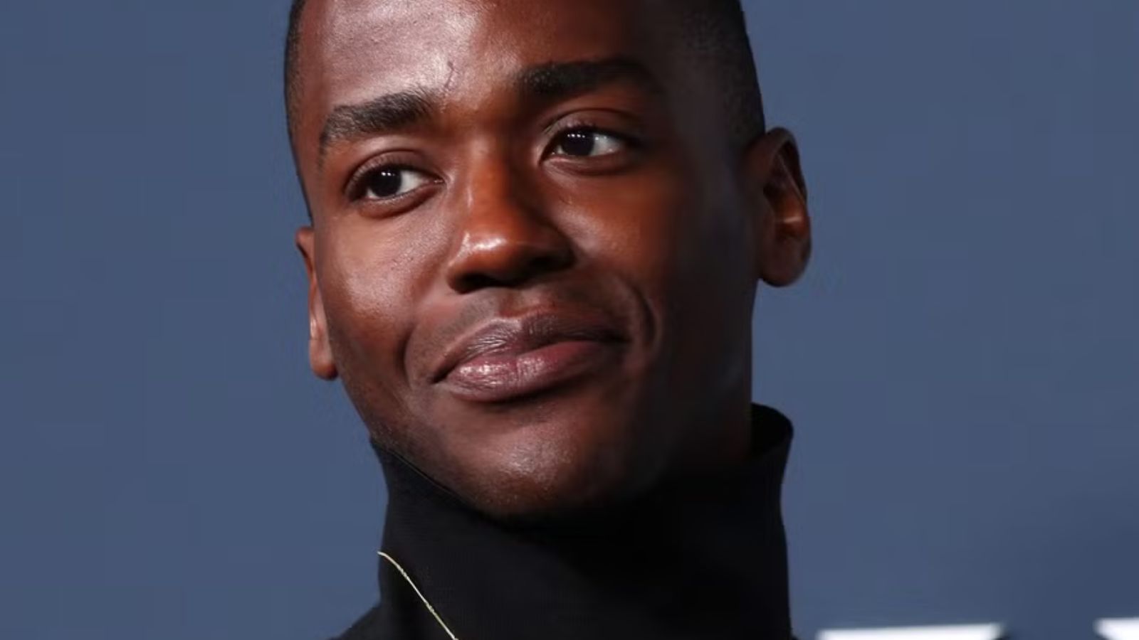 a photo of a dark skin black man smiling into the camera.