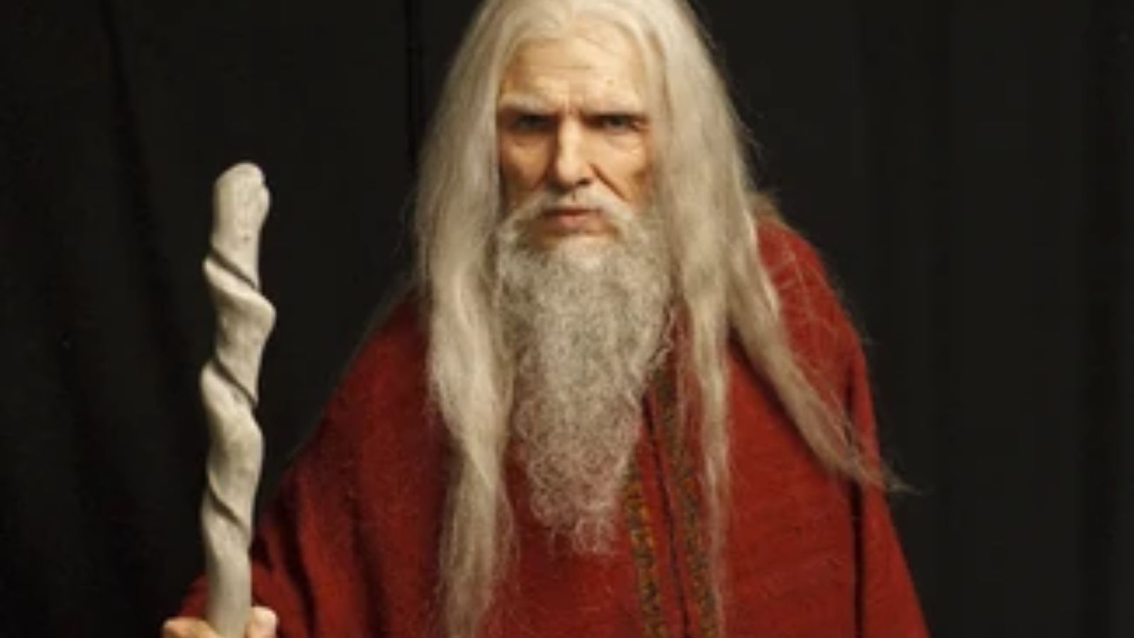 an old white man with a long white hair and beard holding a staff.
