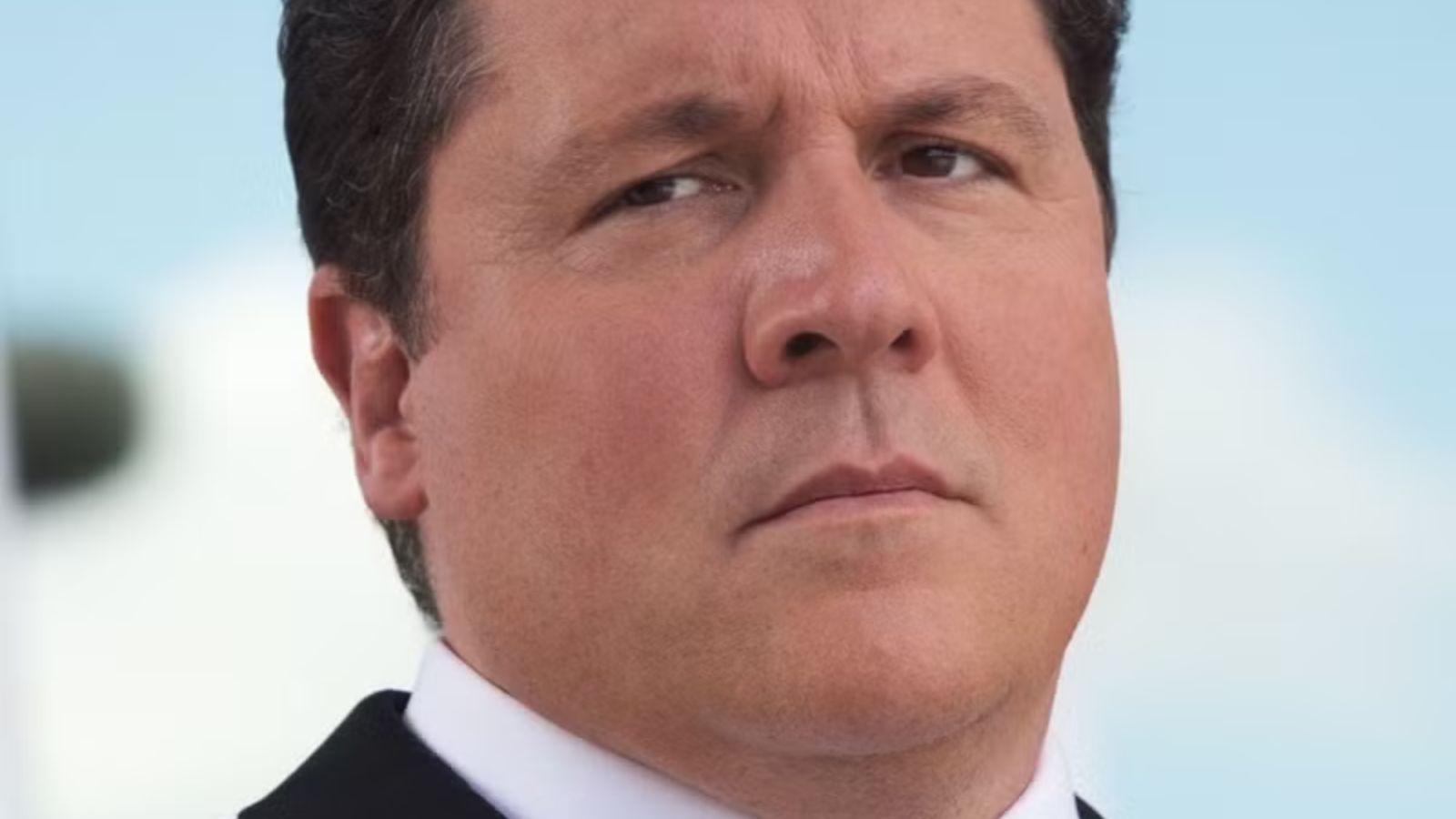 a white plus size man with a dark receding hairline wearing a suit.