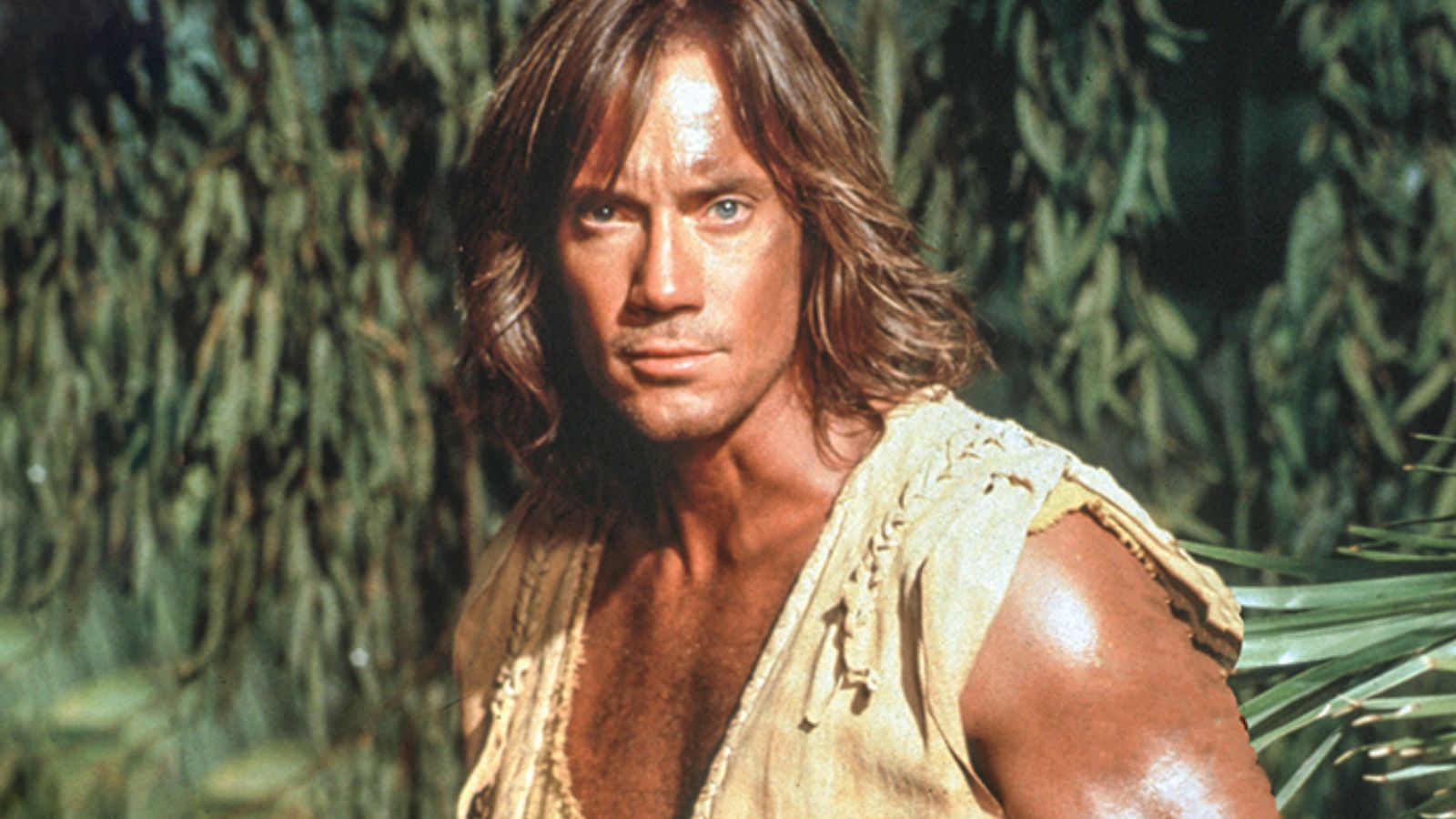 a white muscular man with tan skin and long honey blonde hair.