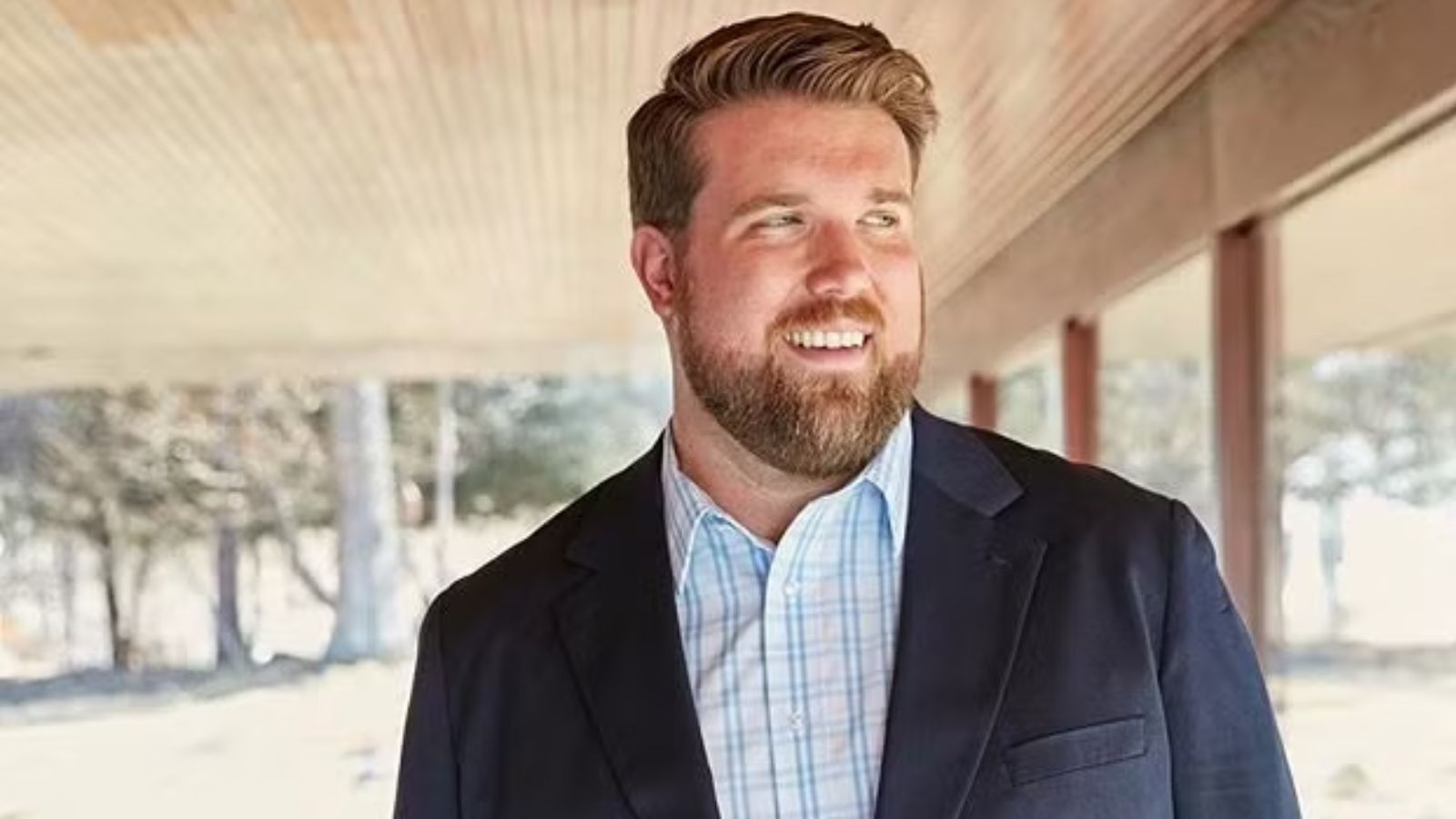 a photo of a plus size white man with honey blonde hair and a neat beard wearing a suit.