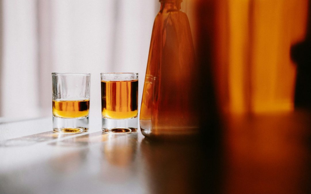 two whiskey glasses with an open bottle.