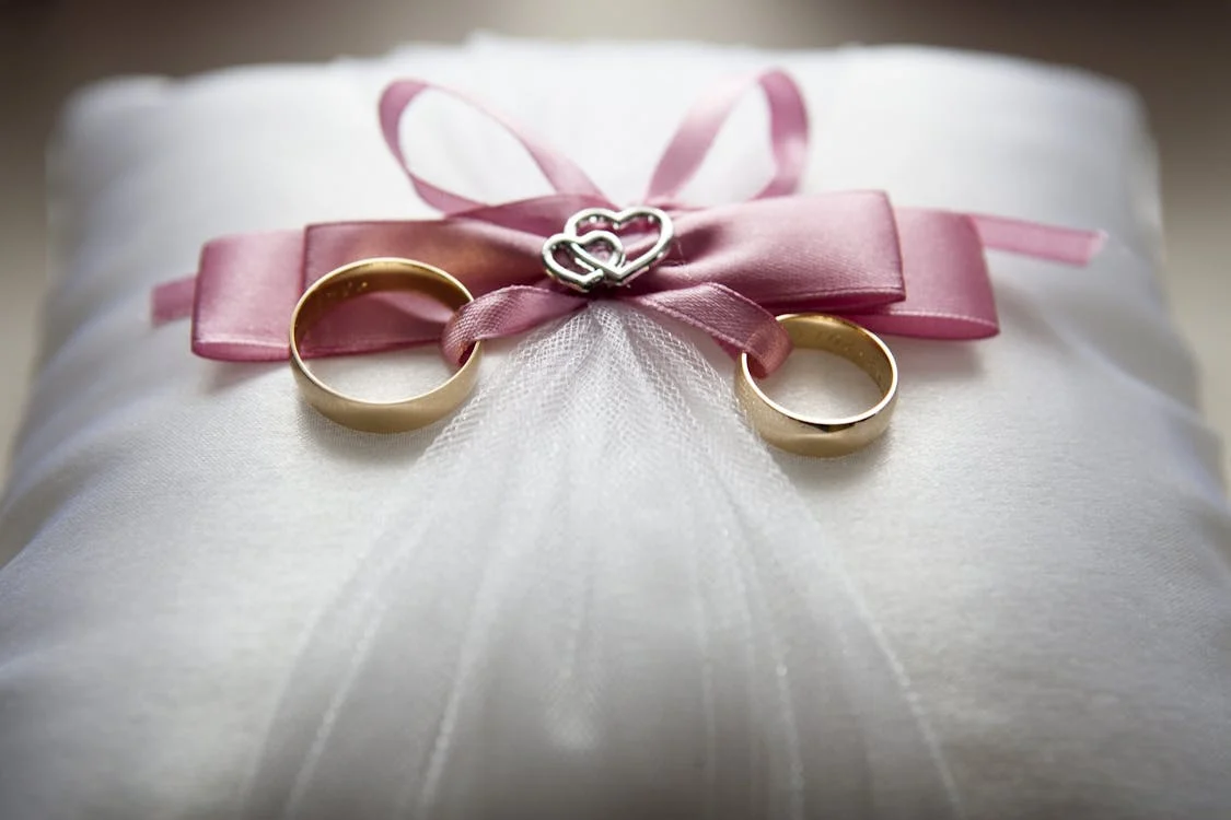wedding rings two wedding rings tied on a pillow with a pink ribbon