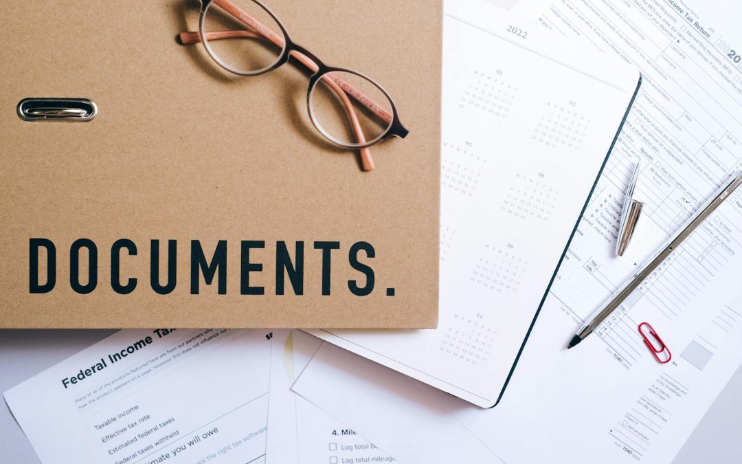 a bunch of papers and on top a manila folder with the words documents on top in black bold letters.