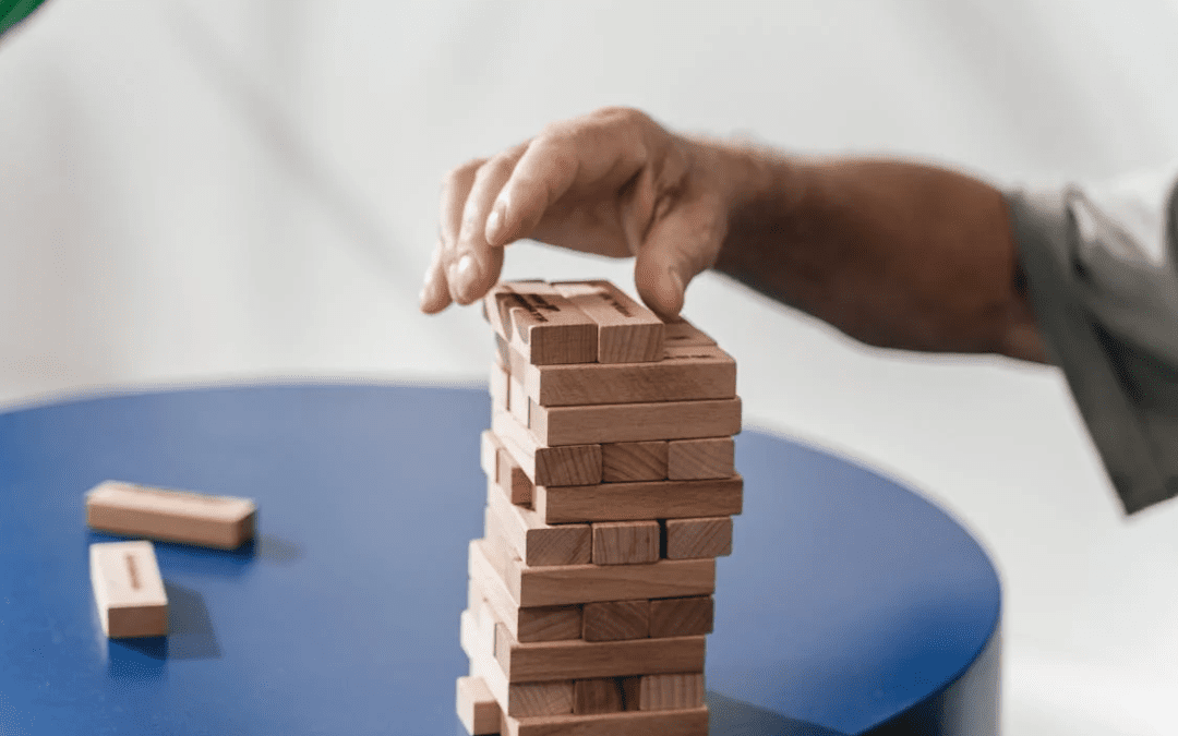 a photo of a man put a block on top of jenga tower