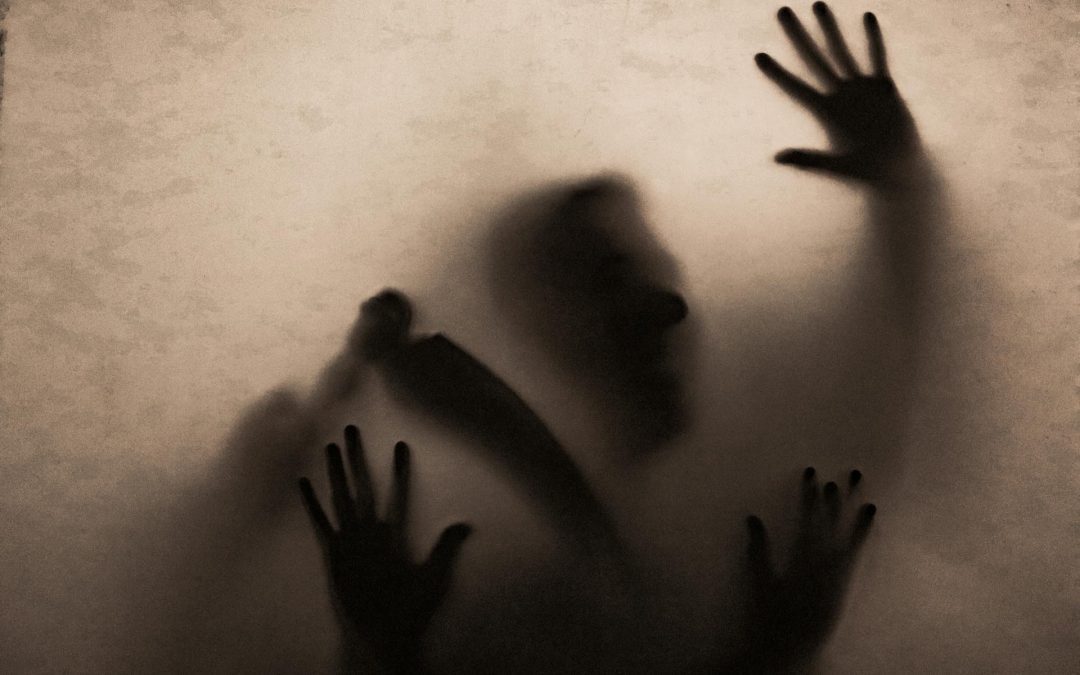 a screen with the eery silhouettes of people pressing against it.