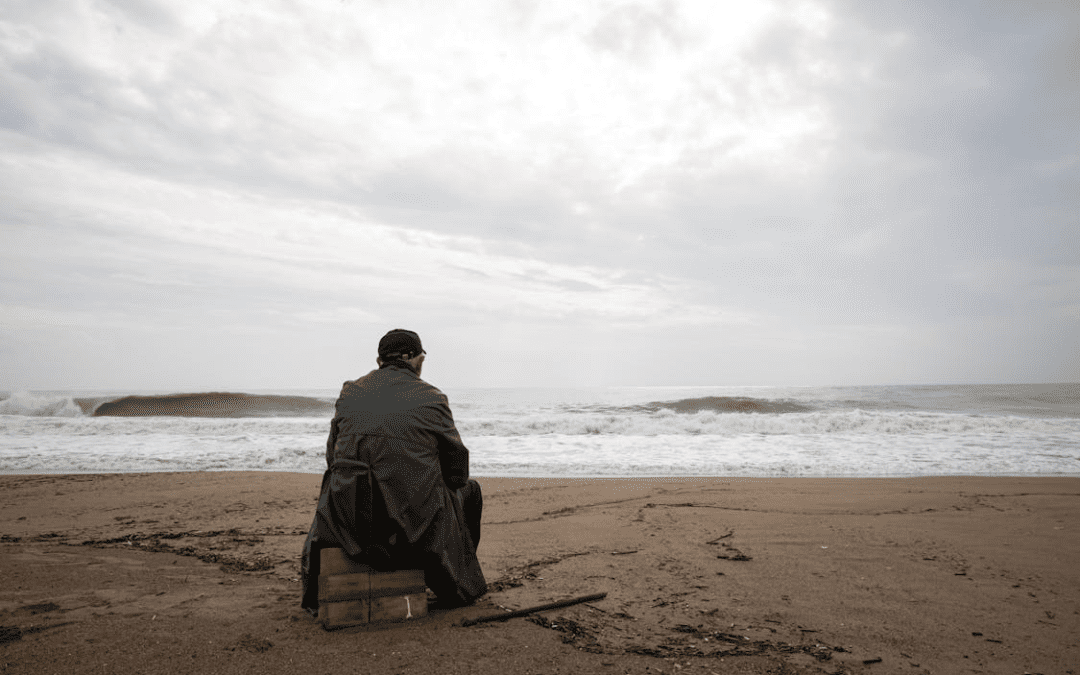 a man sitting on a grim looking beach