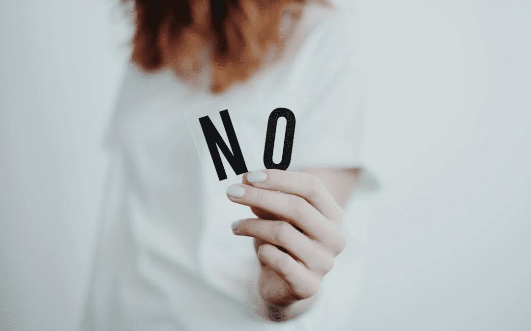 A photo of a woman holding two letter cards that spell no.