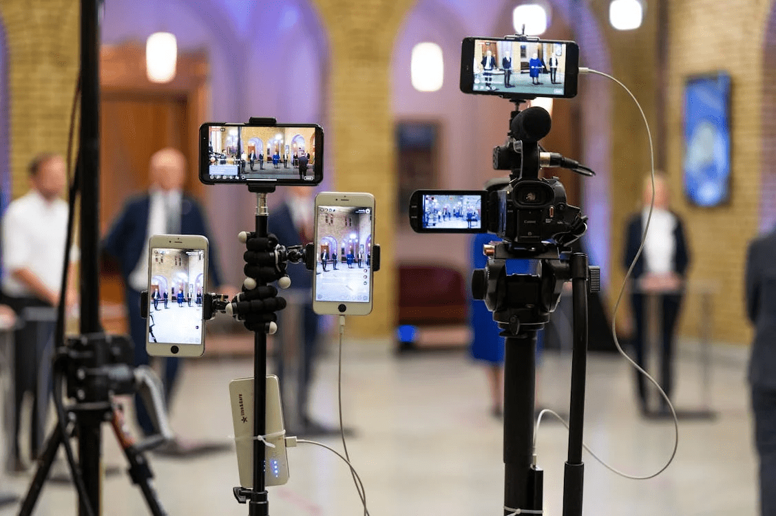 chapter 1: Coming Clean an image that shows phones setting up as cameras on tripods as they film a press conference.