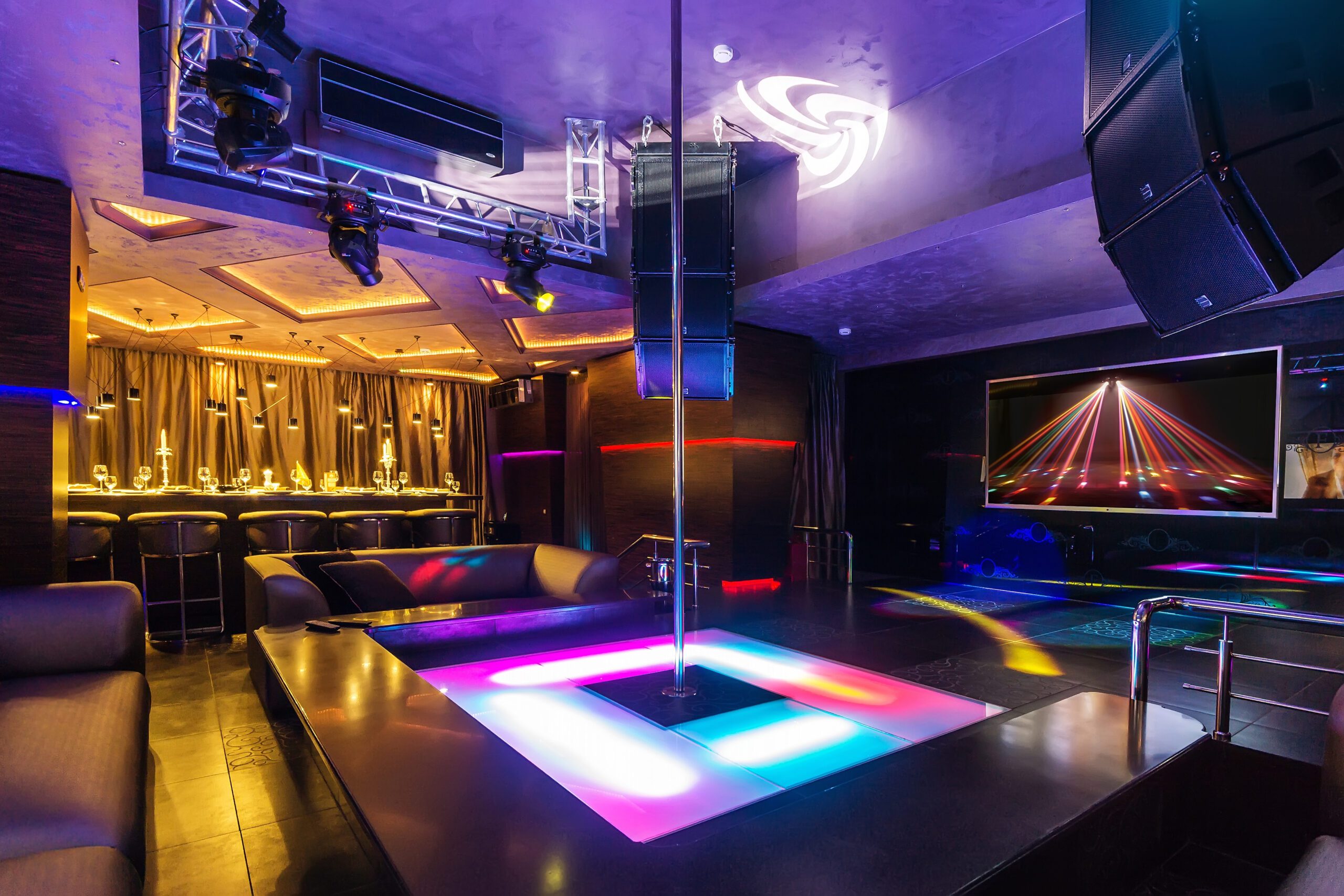 the interior of a strip club. Couches surrounding a stripper pole.