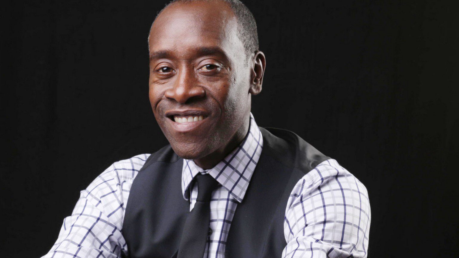 a dark skin black man in a waist coat, tie, and button up shirt.