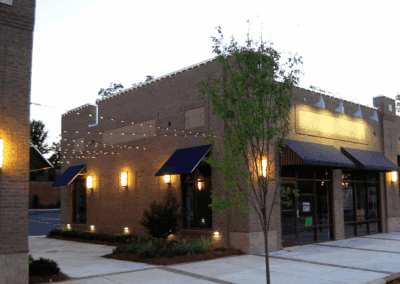an exterior of a brick building with fairy lights outside.