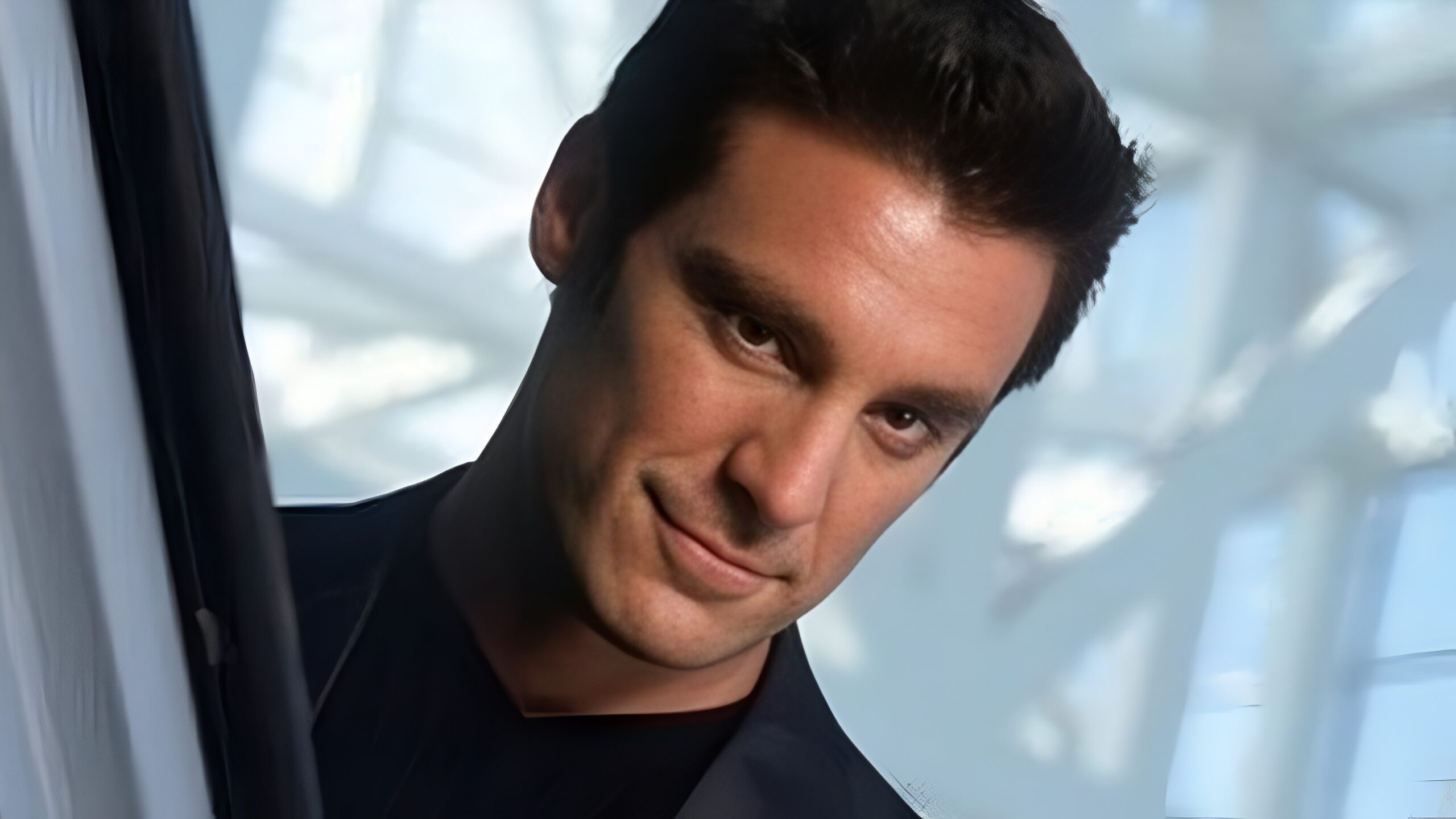 an image of a white man with short dark hair and in a suit. 
