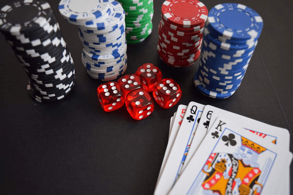 sleight of hand An image of a table that has stacks of colorful poker chips, dice, and playing cards.