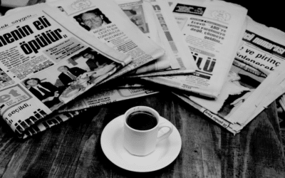 an image of a cup of coffee and stack of newspapers on a table.