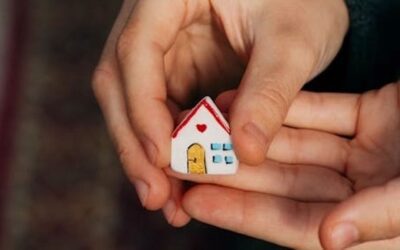 an image of a man holding a little figurine of a cheerful painted house.
