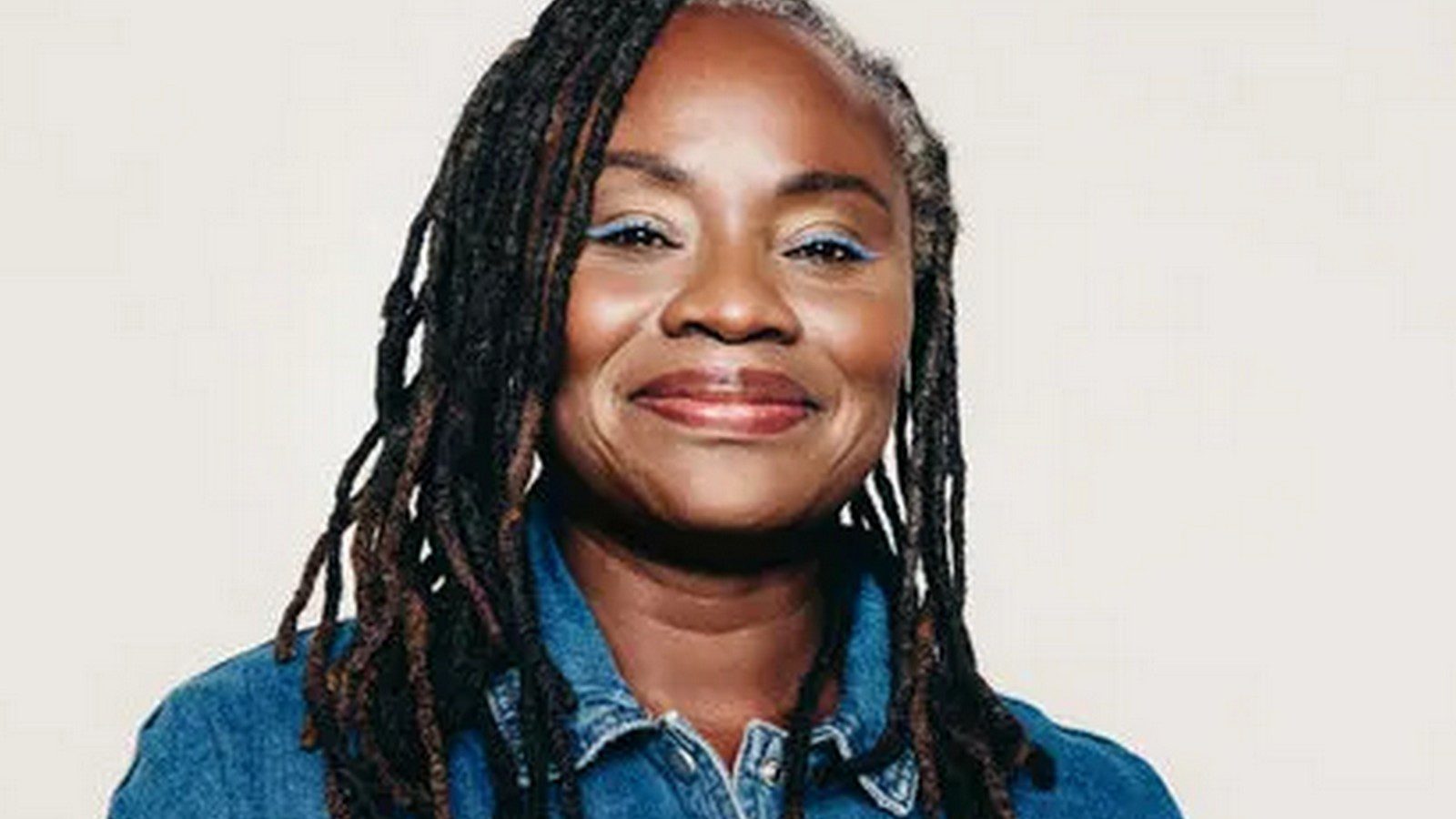 Dionne Baldwin A pretty dark skin black woman in her early to mid 50s with long black and brown locs and gray edges.